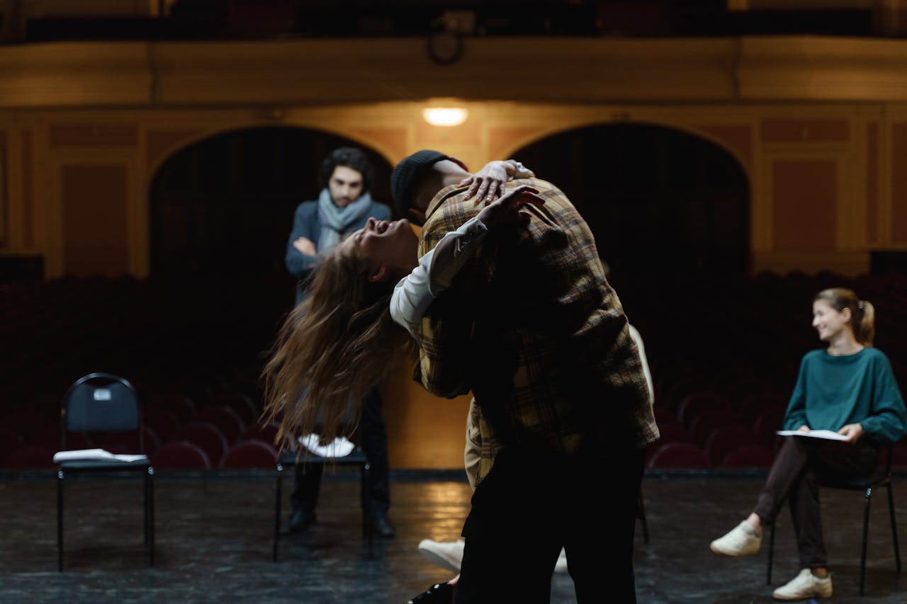 Actors in a dramatic rehearsal on a theater stage, showcasing emotion and performance.